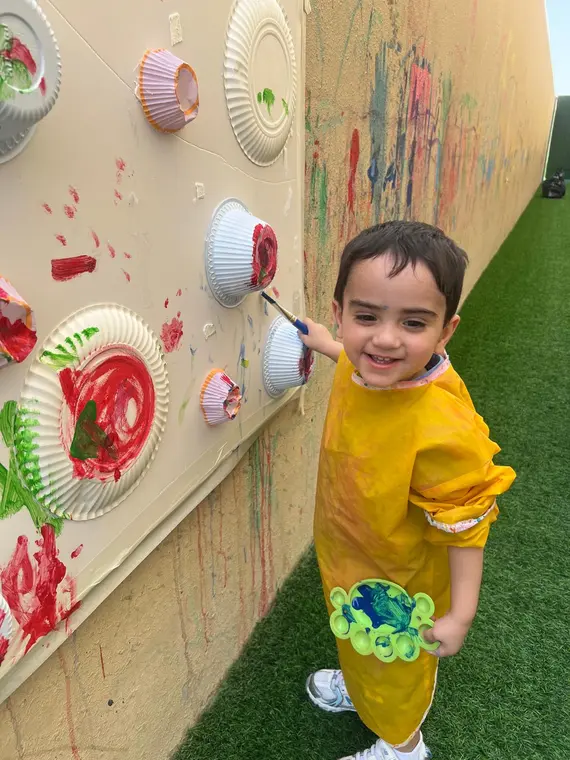 Child painting at the colourful art wall
